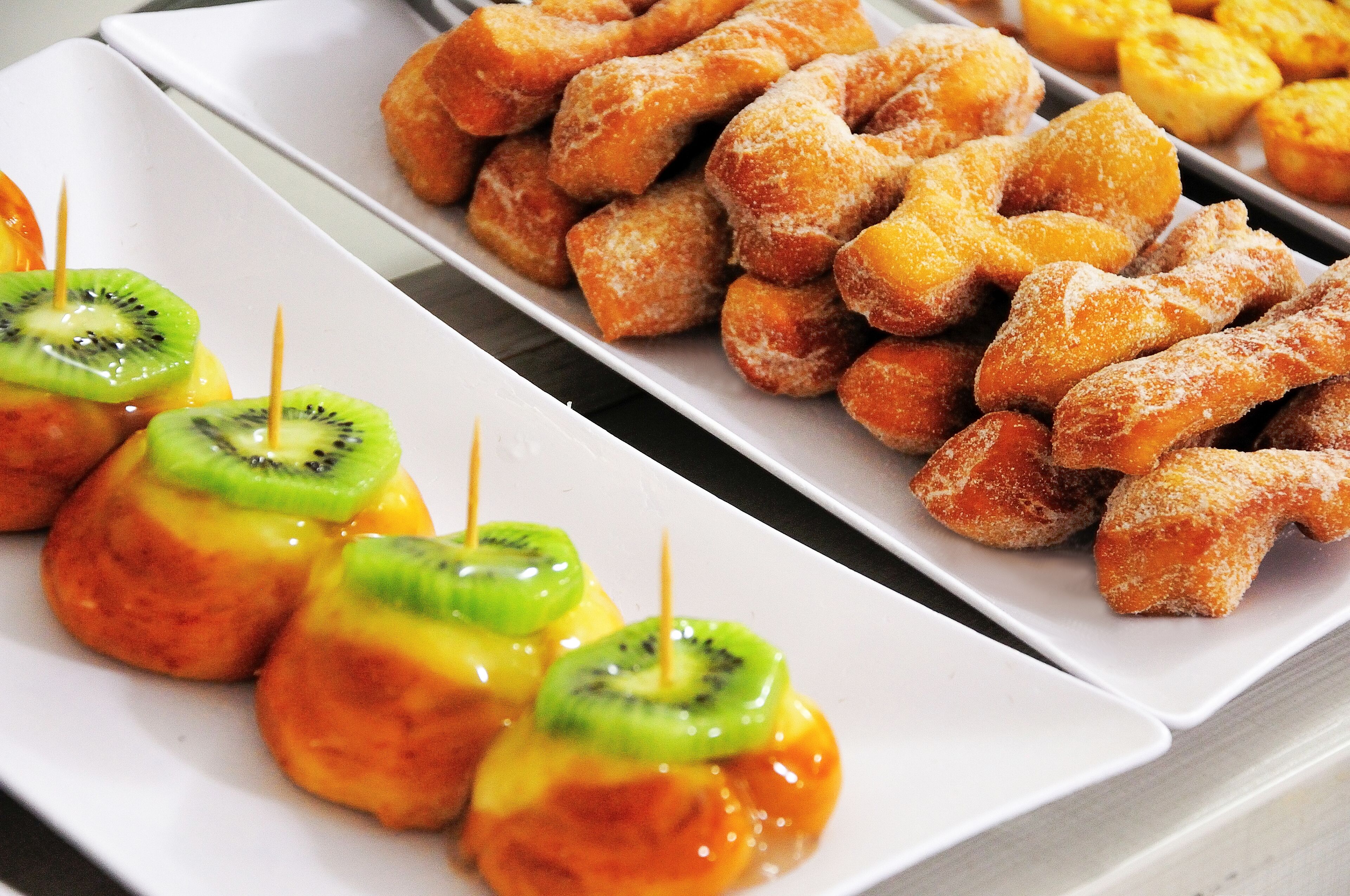 A tray of assorted pastries including glazed donuts and fruit-topped treats.