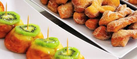 A tray of assorted pastries including glazed donuts and fruit-topped treats.
