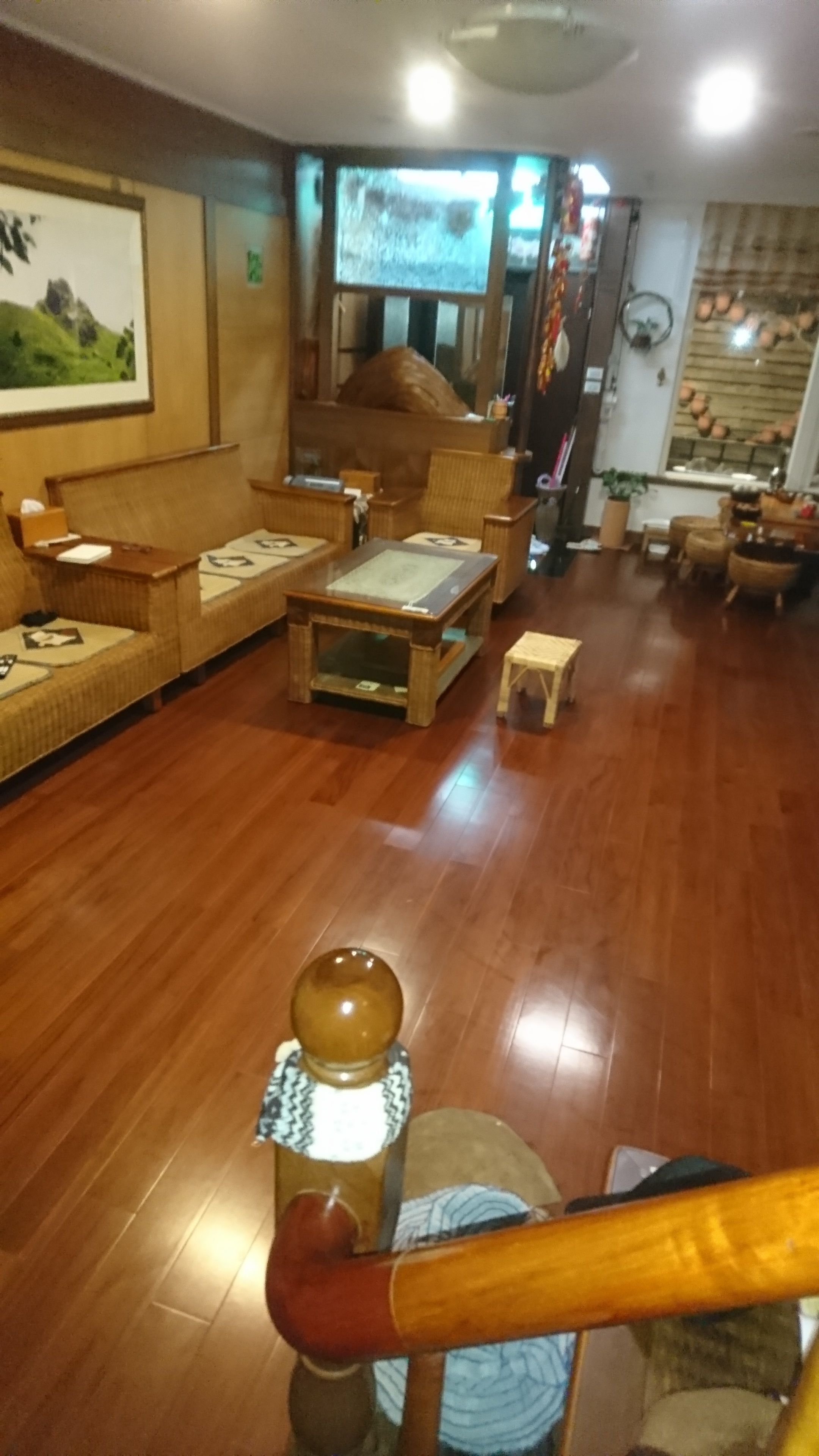 Un salon chaleureux, doté de meubles en bois, d’une grande fenêtre et d’un ventilateur de plafond.