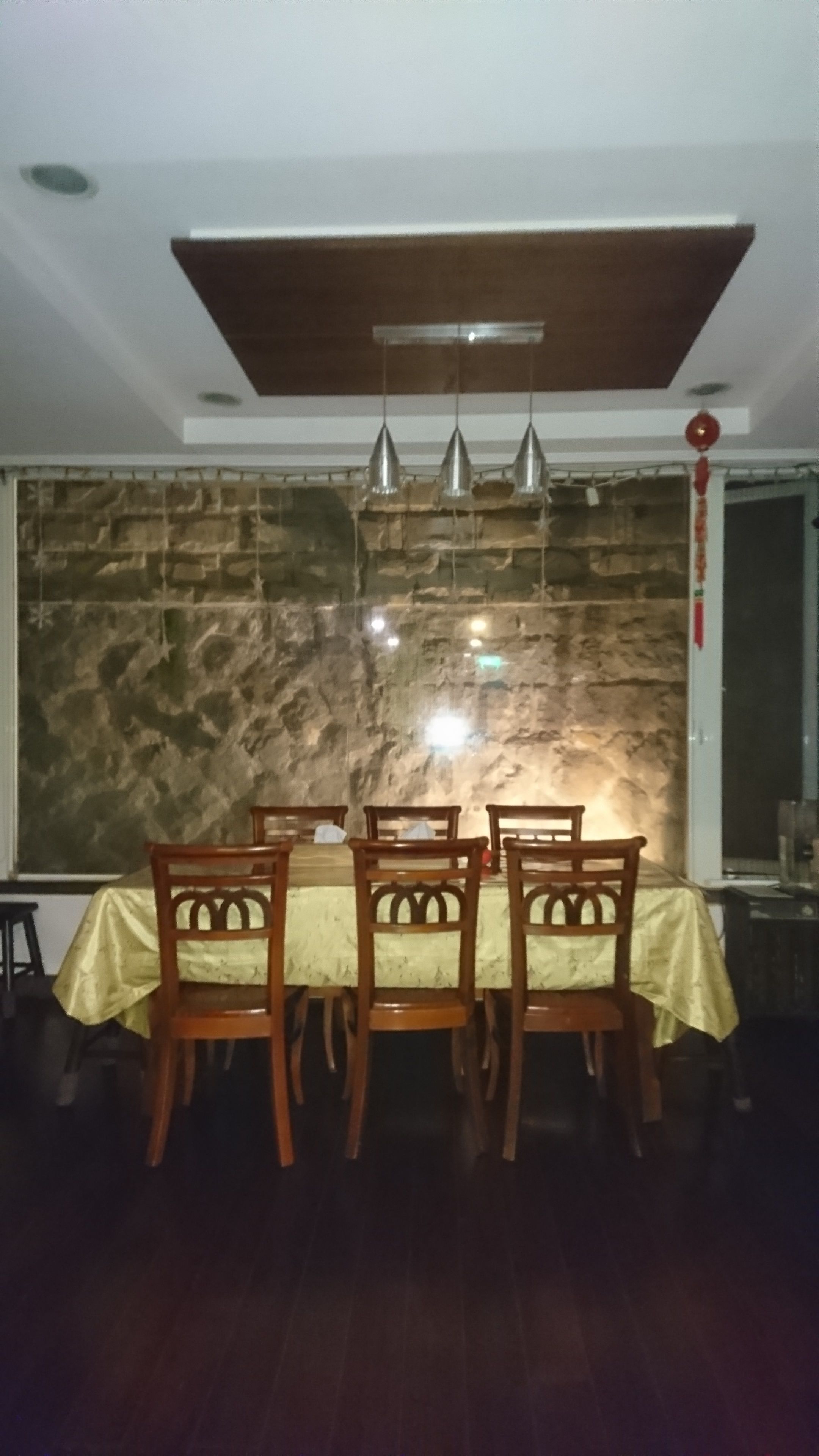 A dining area with a table set for four, wooden chairs, and pendant lights.