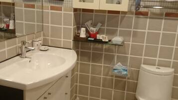 A bathroom with a white sink, mirror, cabinets, and a toilet.