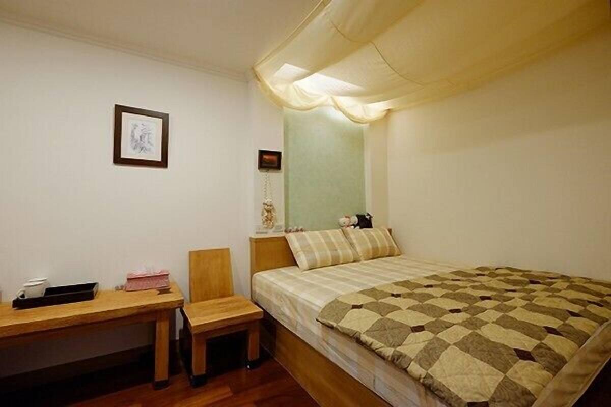 Ein kleines, ordentlich eingerichtetes Schlafzimmer mit einem Bett, einem Schreibtisch und einem Stuhl.