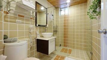 A bathroom with a toilet, sink, mirror, shower, and tiled walls.