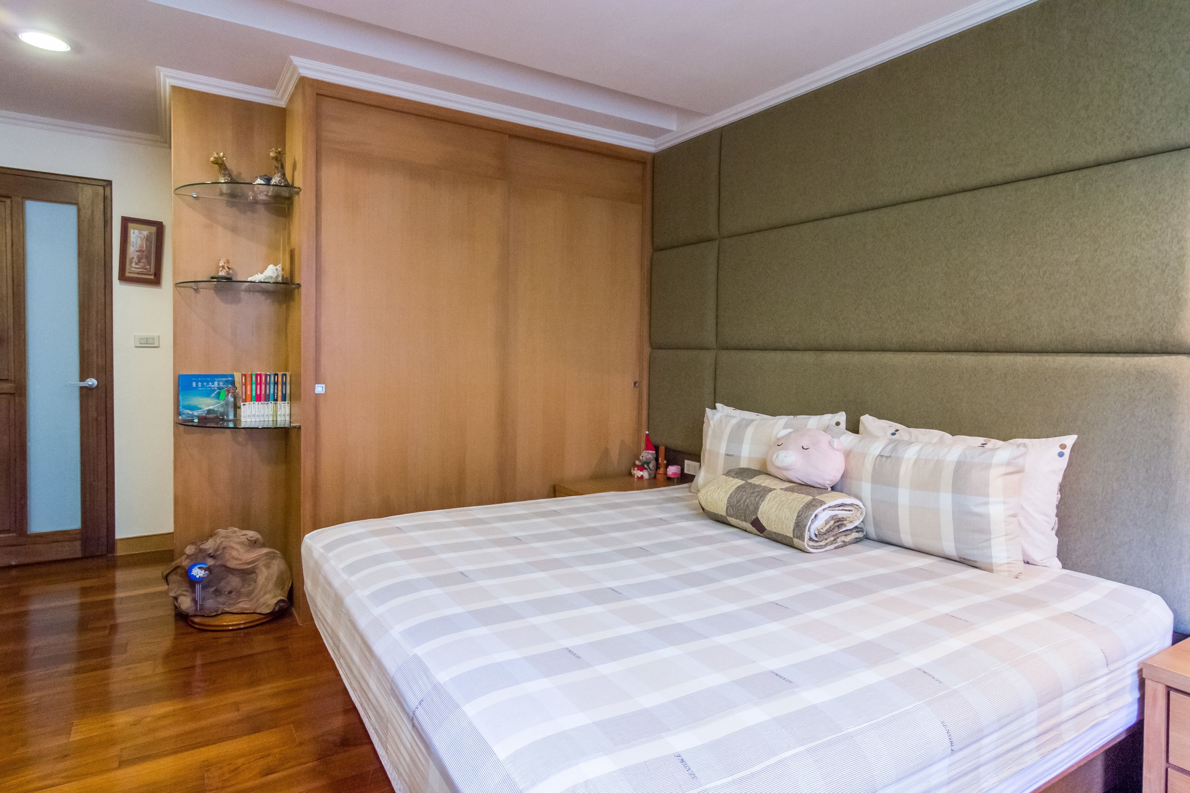 Ein Schlafzimmer mit einem großen Bett, einem Holzschrank und Regalen mit Toilettenartikeln.