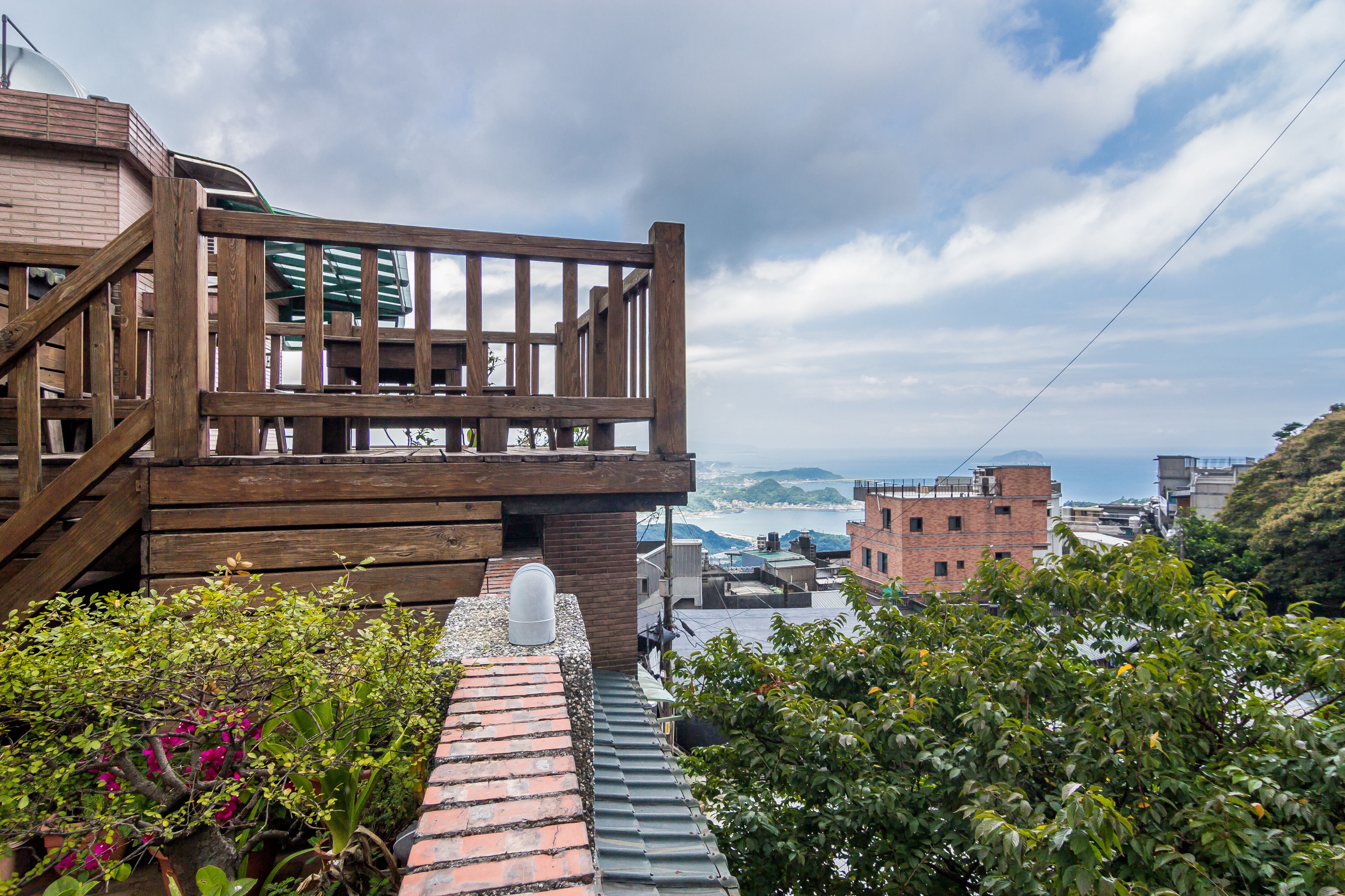 Eine Holzterrasse mit Blick auf das Meer und Gebäude im Hintergrund.