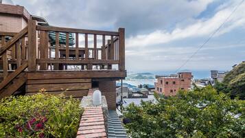 Eine Holzterrasse mit Blick auf das Meer und Gebäude im Hintergrund.