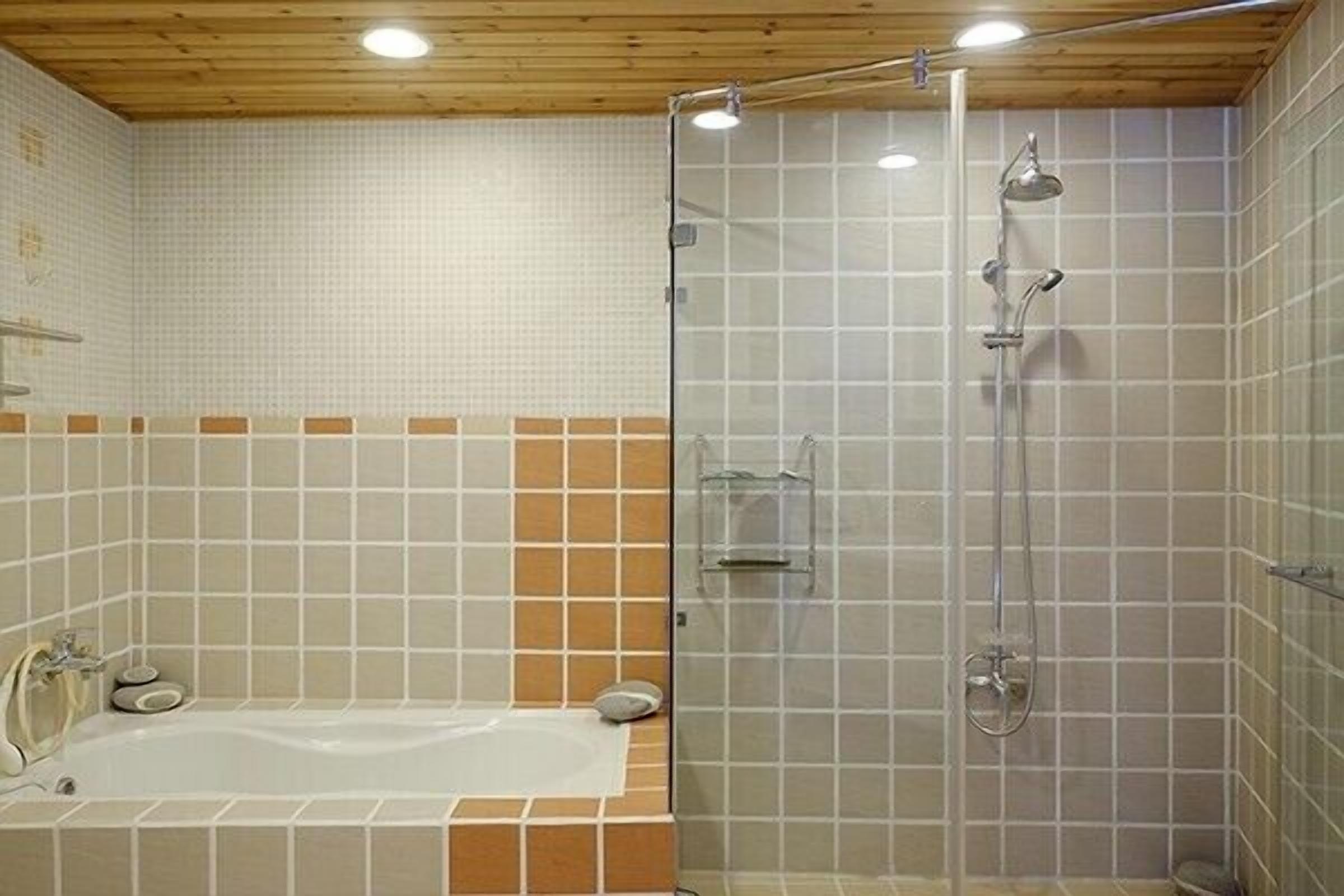A bathroom with a bathtub, a glass shower enclosure, and tiled walls.