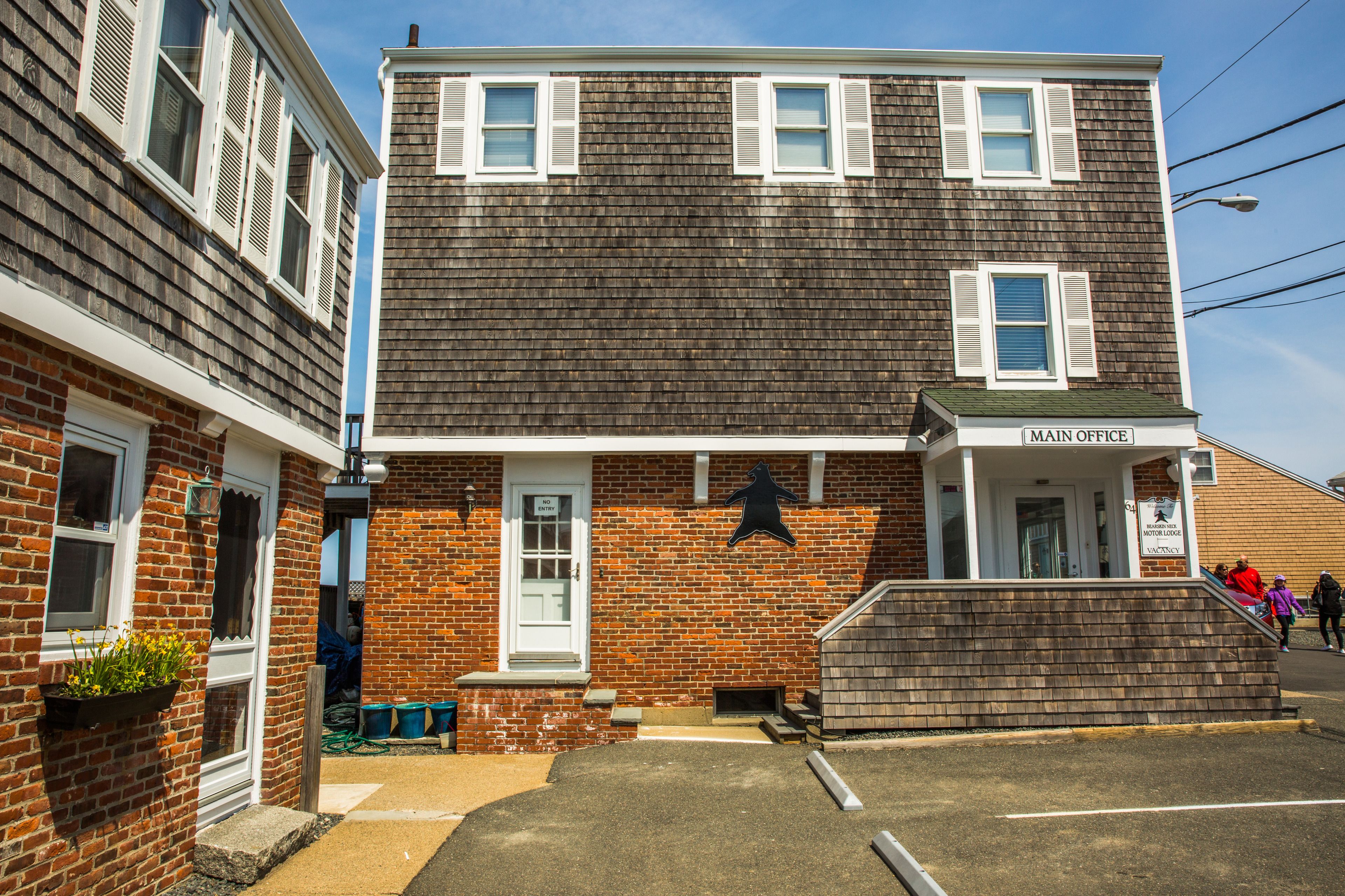 A two-story building with a brick facade, a white door, and a sign indicating the main office.