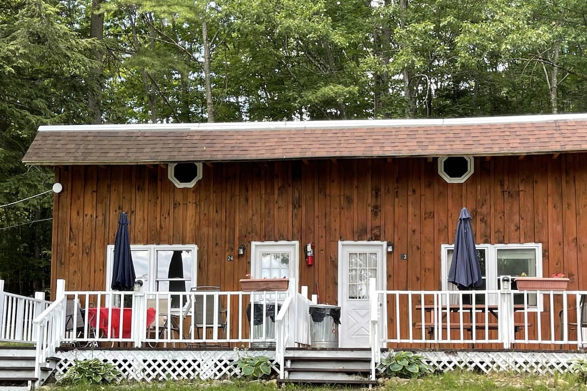 A wooden cabin with a porch, two doors, and a small deck.