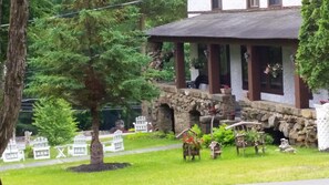 A stone building with a covered porch, surrounded by greenery and white chairs. - Rock Castle Resort (Lake George)
