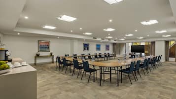 A conference room with a long table, chairs, a TV, and framed pictures on the wall.