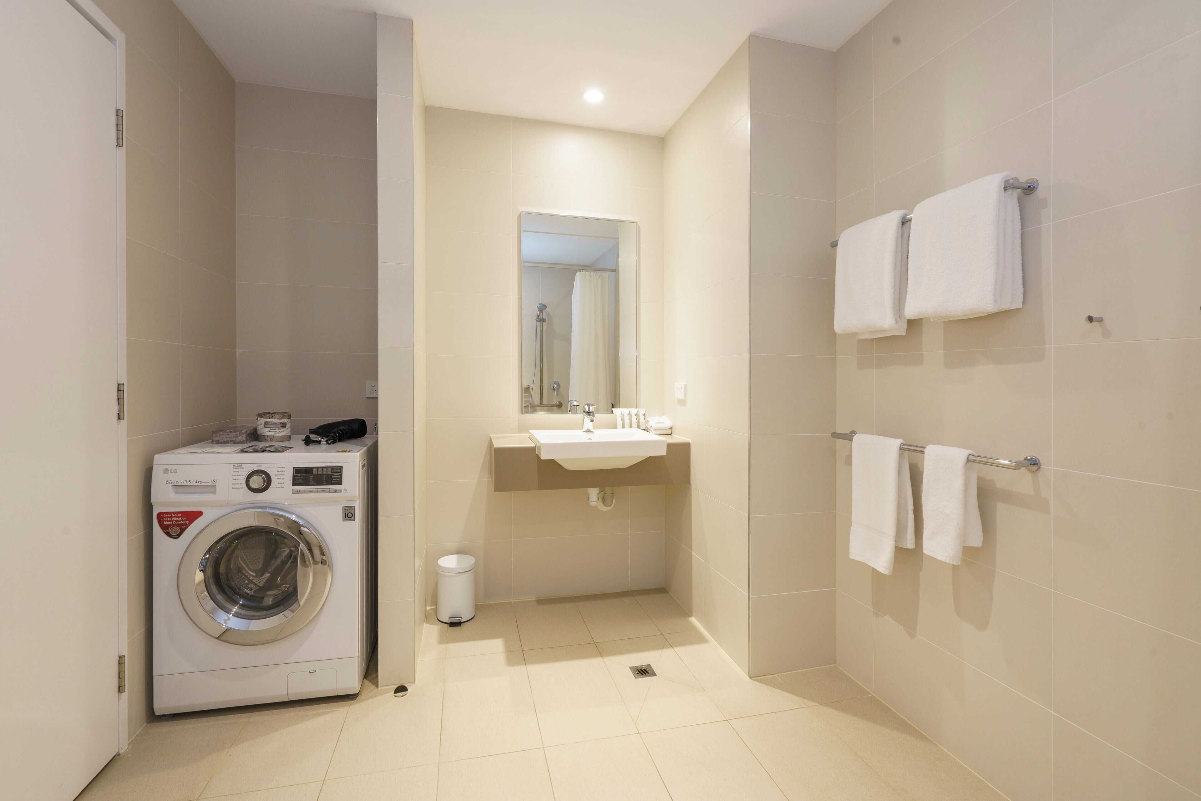 A compact bathroom with a washing machine, a sink, and a towel rack.