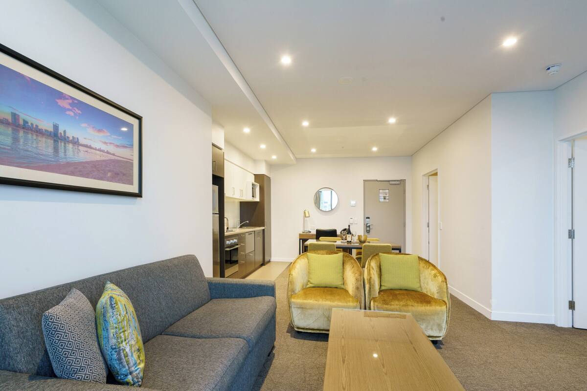 A modern living room with a sofa, armchairs, a coffee table, and a dining area with a table and chairs.