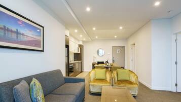 A modern living room with a sofa, armchairs, a coffee table, and a dining area with a table and chairs.