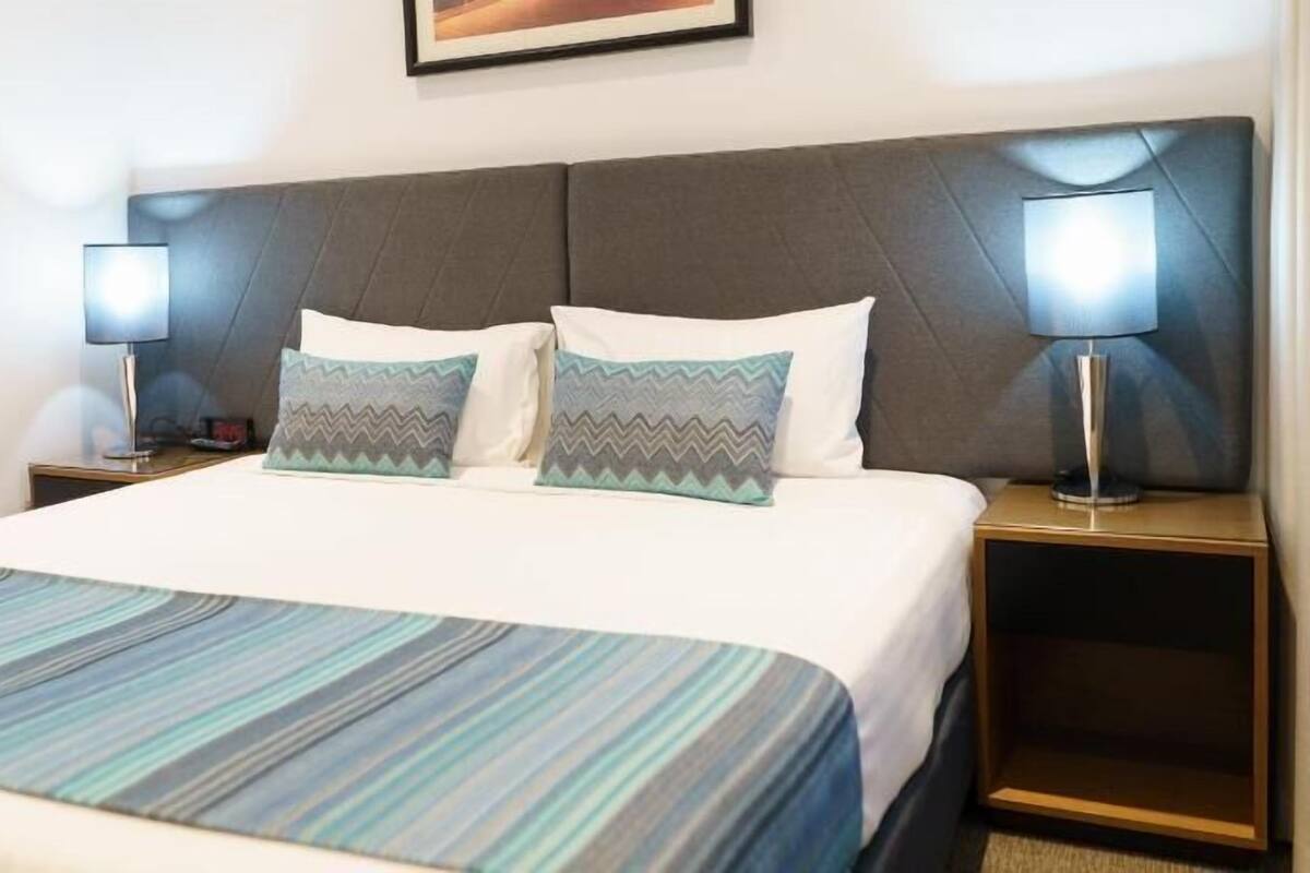 A hotel room with a large bed, two bedside tables with lamps, and a framed picture on the wall.