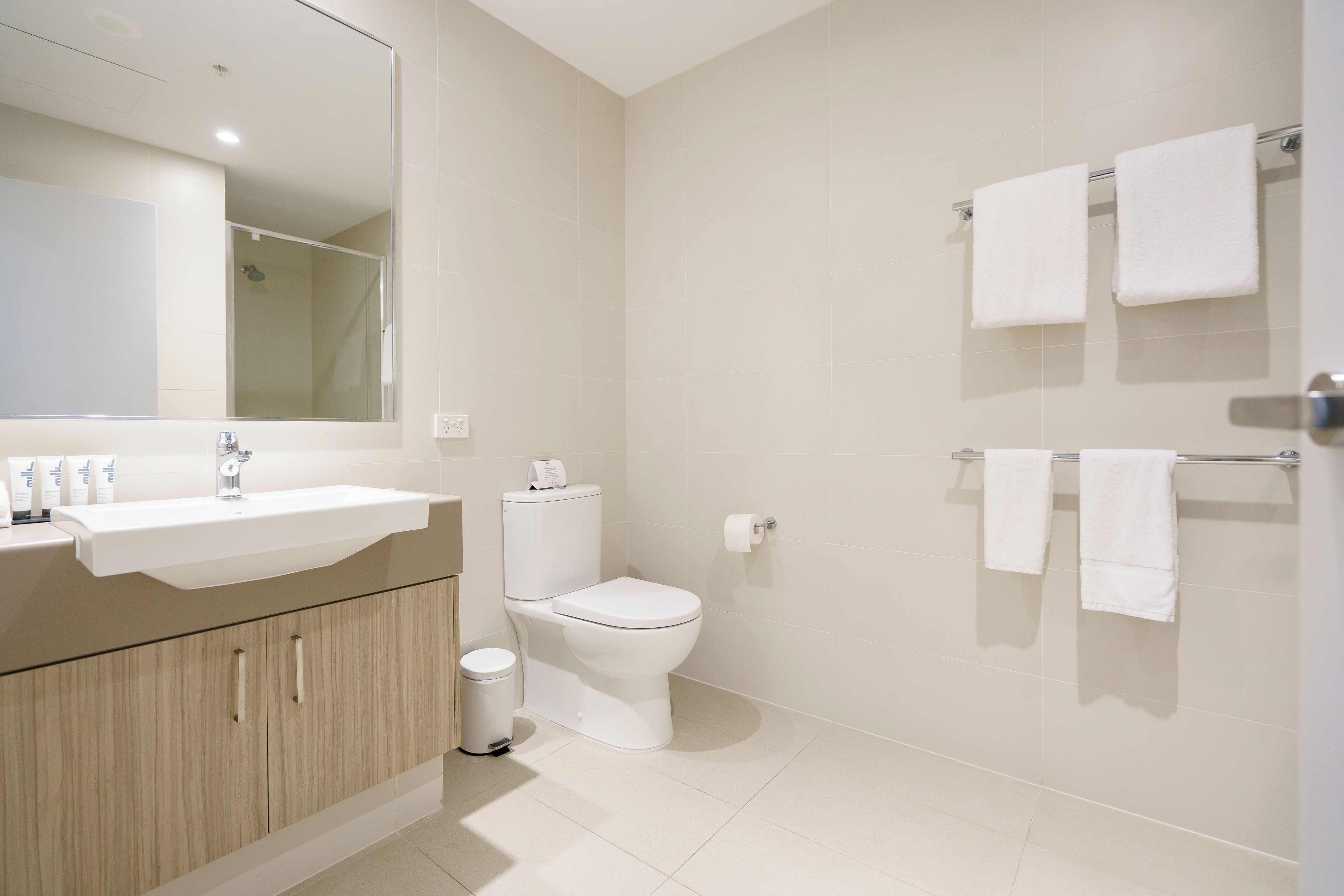 A modern bathroom with a sink, mirror, toilet, and shower.