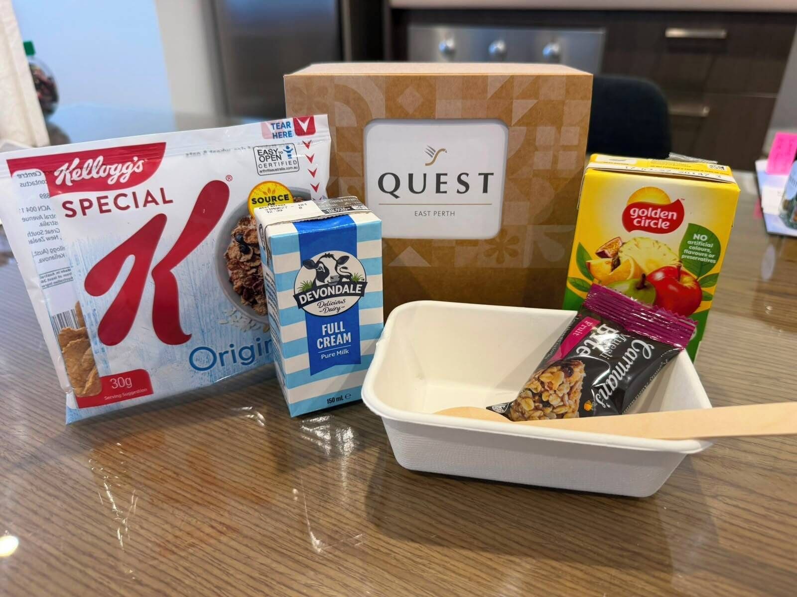 A table with various food items including a box of Kellogg's Special K, Devondale full cream milk, Quest cereal, and a box of Golden Circle.