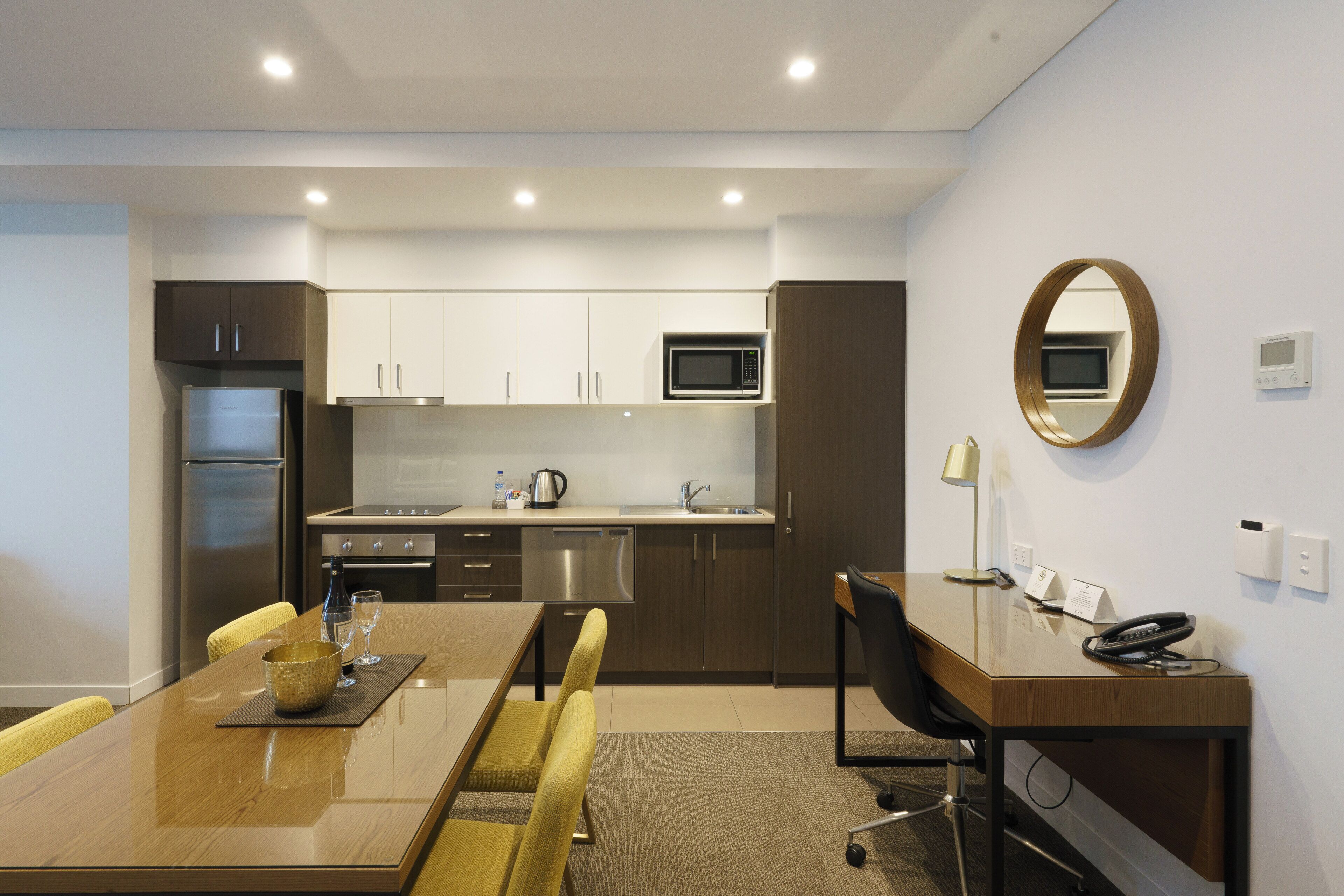 A modern kitchen with a dining area, including a table, chairs, and a microwave.