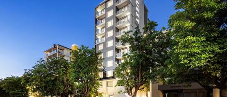 A multi-story hotel with balconies, a well-maintained lawn, and a clear sky.