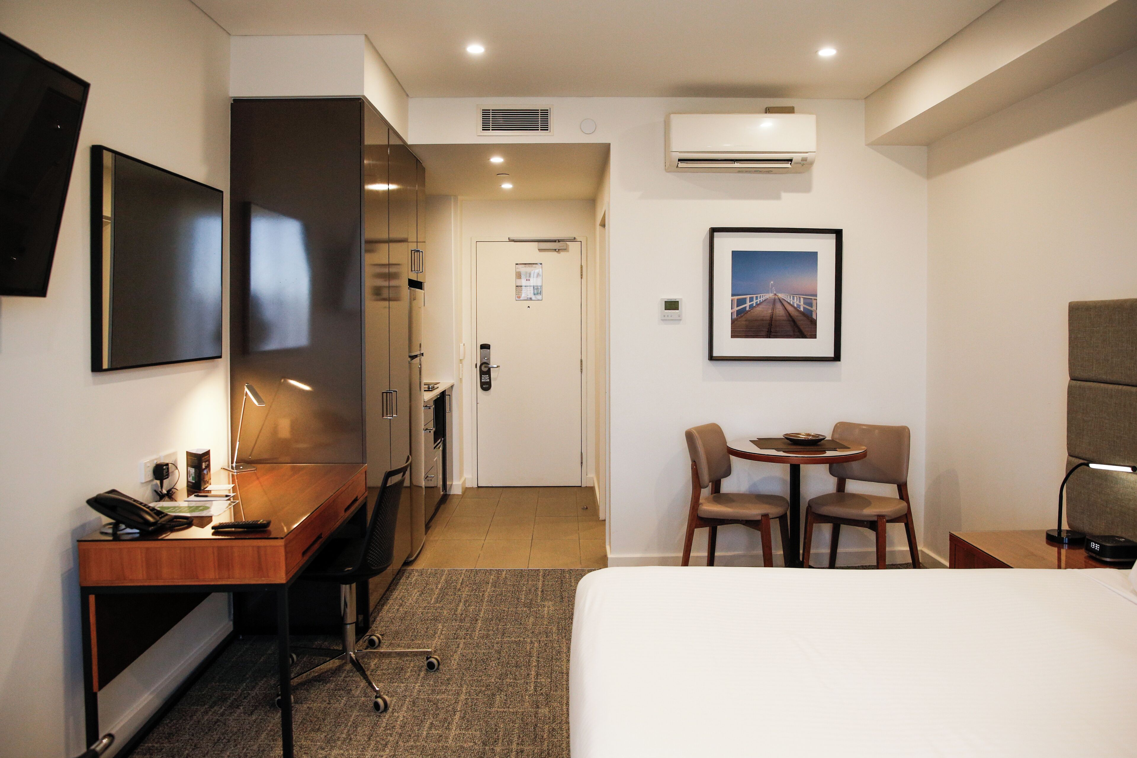 Habitación de hotel con cama, escritorio, silla y una pequeña mesa con sillas.