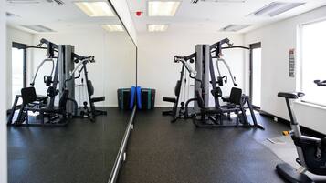 Un gimnasio con paredes de espejo, equipamiento de ejercicio y una cinta de correr.