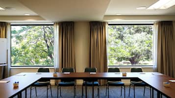 A conference room with a long table, chairs, and a view of trees through large windows.