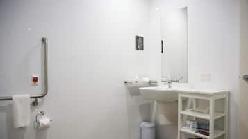 A modern bathroom with a toilet, sink, mirror, and a white shelf unit.