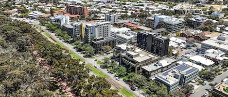 An aerial view of a cityscape with modern buildings, roads, and green spaces.