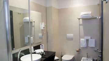 Un baño moderno con ducha de vidrio, lavamanos con espejo e inodoro.