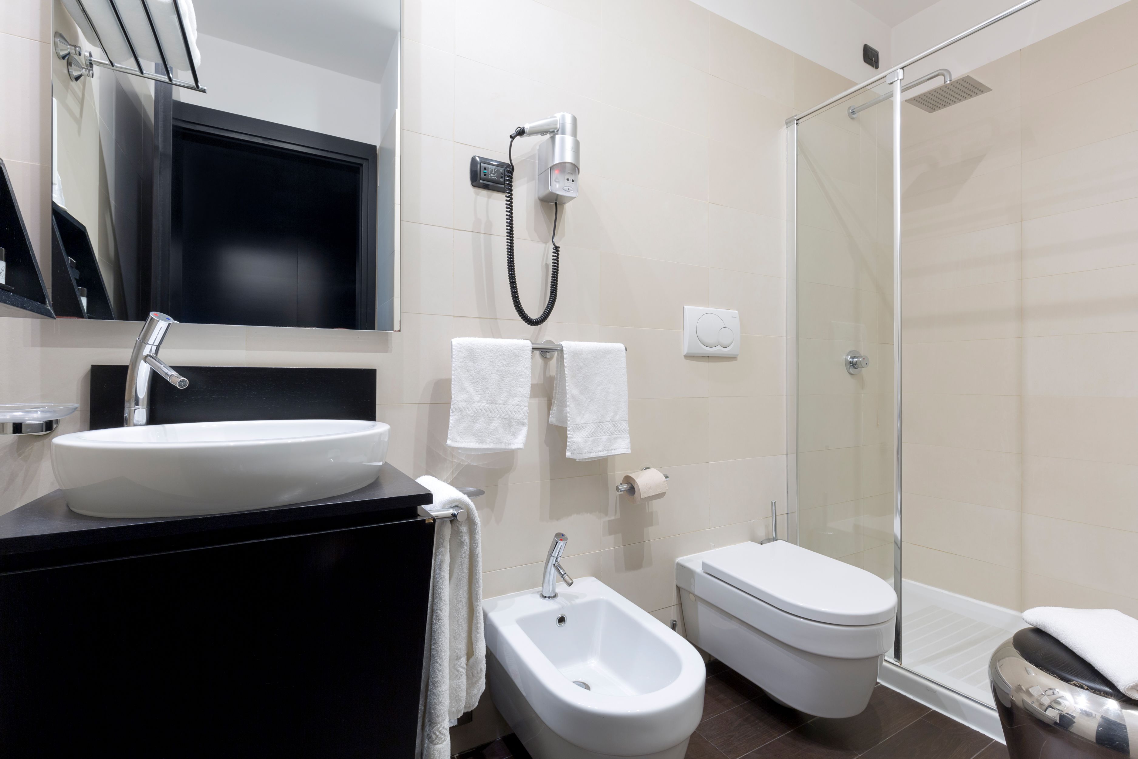 Ein modernes Badezimmer mit Waschbecken, Bidet, Toilette und Duschkabine aus Glas.