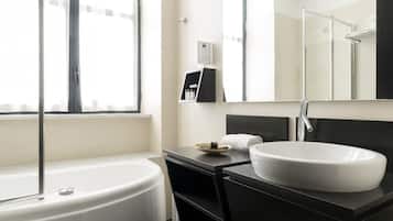 Un baño moderno con bañera, un espejo grande y un lavamanos blanco.