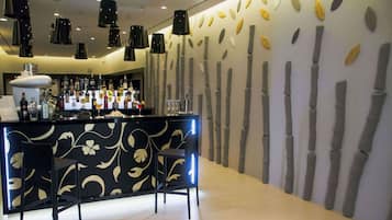 Eine Bar mit einer schwarzen Theke, zahlreichen Flaschen und zwei schwarzen Barhocker.
