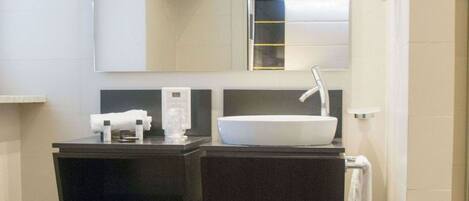 A bathroom with a dark wood vanity, a white sink, and a mirror above it.