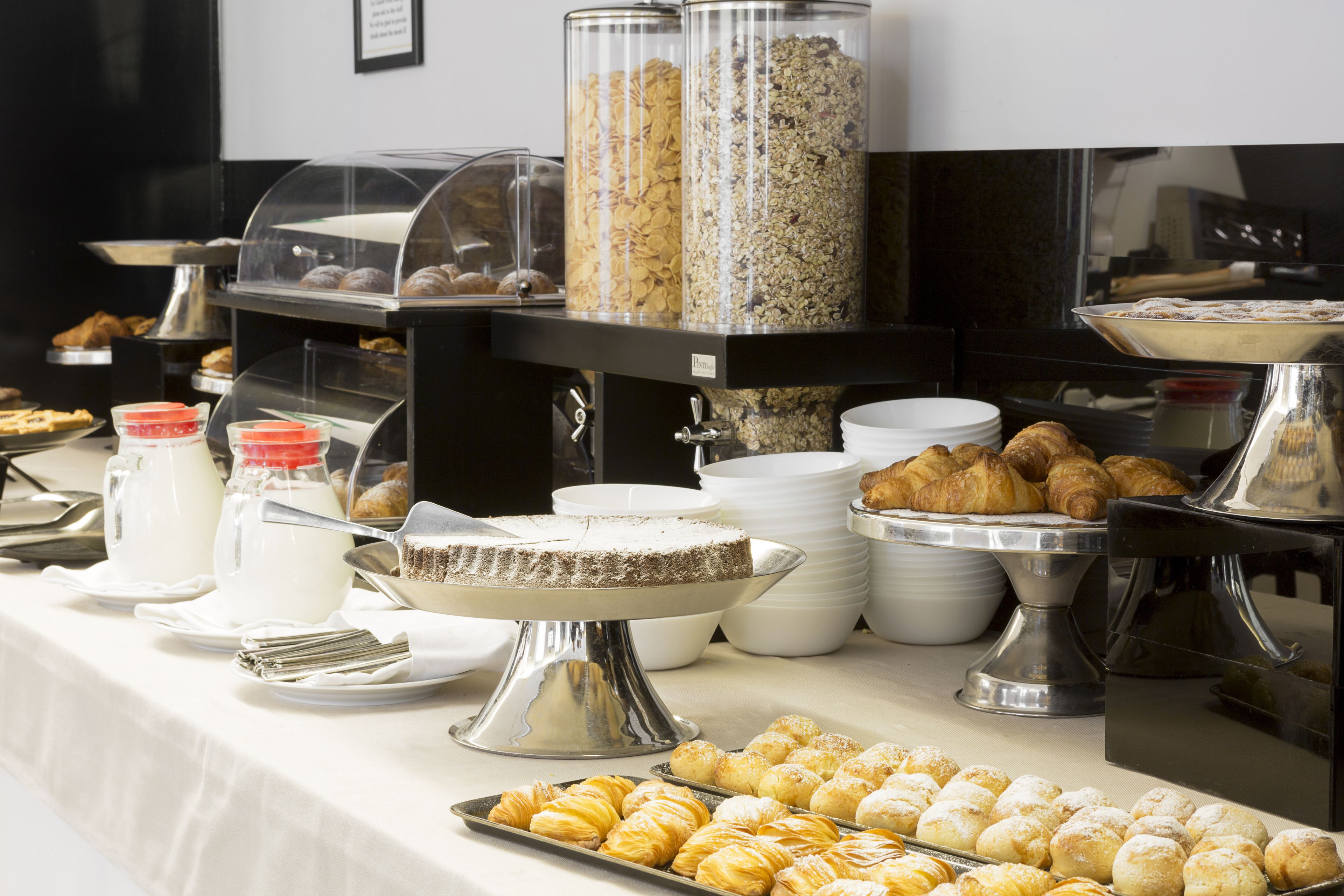Un bufé con diferentes alimentos, incluyendo pasteles, cereales y productos lácteos.