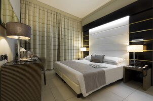 Una moderna camera d'albergo con un letto grande, due comodini, una scrivania e una sedia.