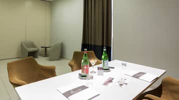Un salón de conferencias con una mesa blanca, dos sillas, una botella de agua, un vaso y un menú.