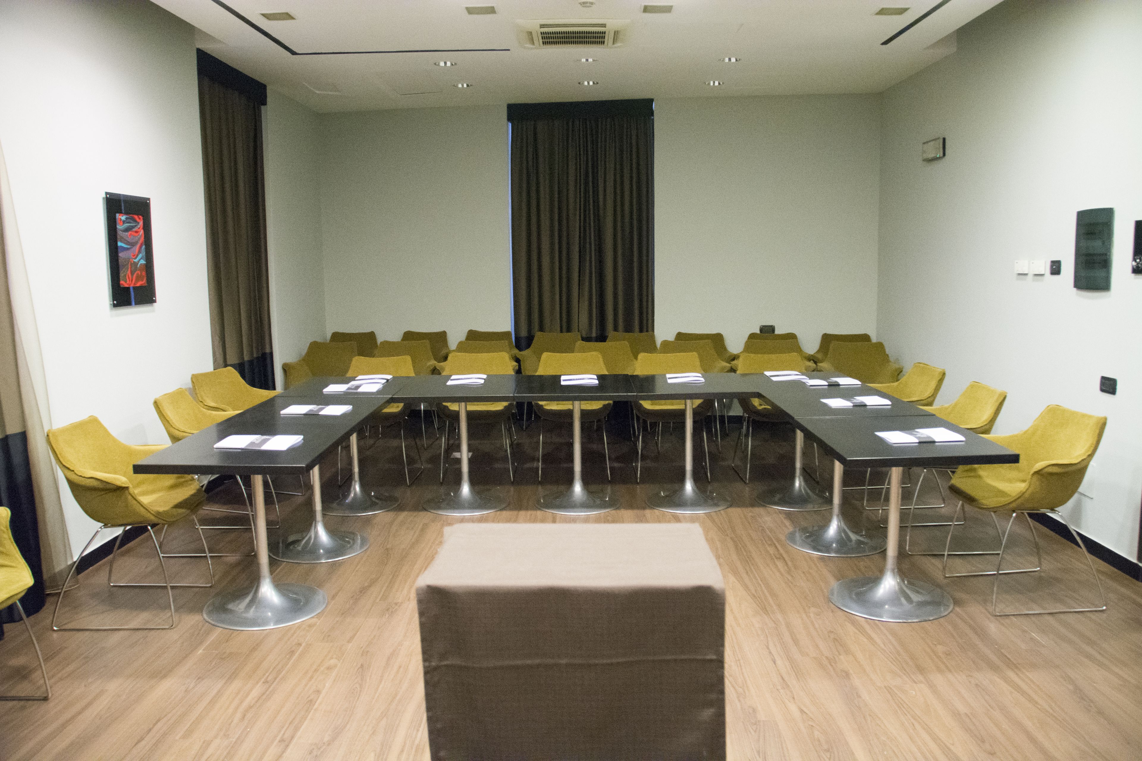 Un salón de conferencias con una larga mesa, sillas amarillas y una alfombra color beige.