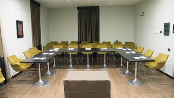 Un salón de conferencias con una larga mesa, sillas amarillas y una alfombra color beige.