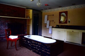 A bathroom with a large bathtub, a wooden chair, a mirror, and a towel rack. - New Hampshire Mountain Inn (Wilmot)