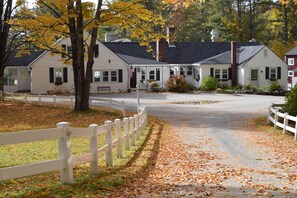 A white building with a porch, surrounded by trees with yellow leaves. - New Hampshire Mountain Inn (Wilmot)