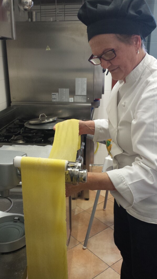 A chef in a professional kitchen with stainless steel appliances and a tiled floor. - Agriturismo ai Carpini (Marcon)