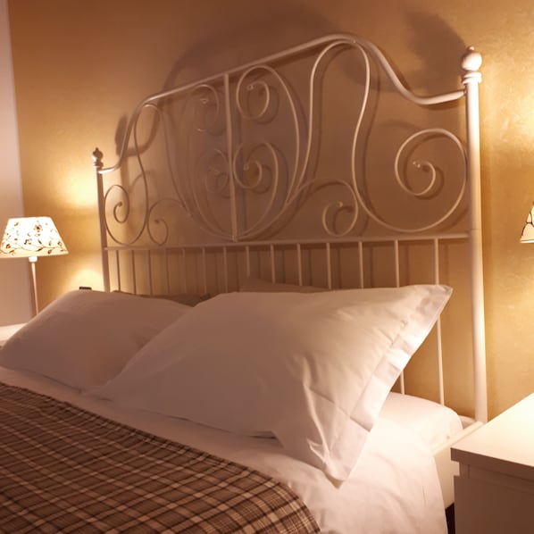 A bed with white linens and a metal headboard with decorative scrollwork. - Agriturismo ai Carpini (Marcon)