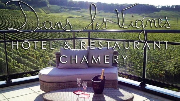 A terrace with wicker furniture, a bottle of champagne, and a glass, overlooking a vineyard. - Dans Les Vignes (Chamery)