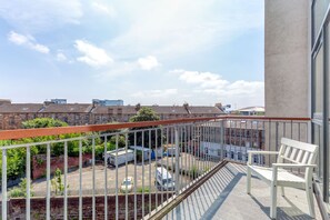A balcony with a white bench, a view of a parking area, and residential buildings in the background. - Executive 7 Apartments (Glasgow)