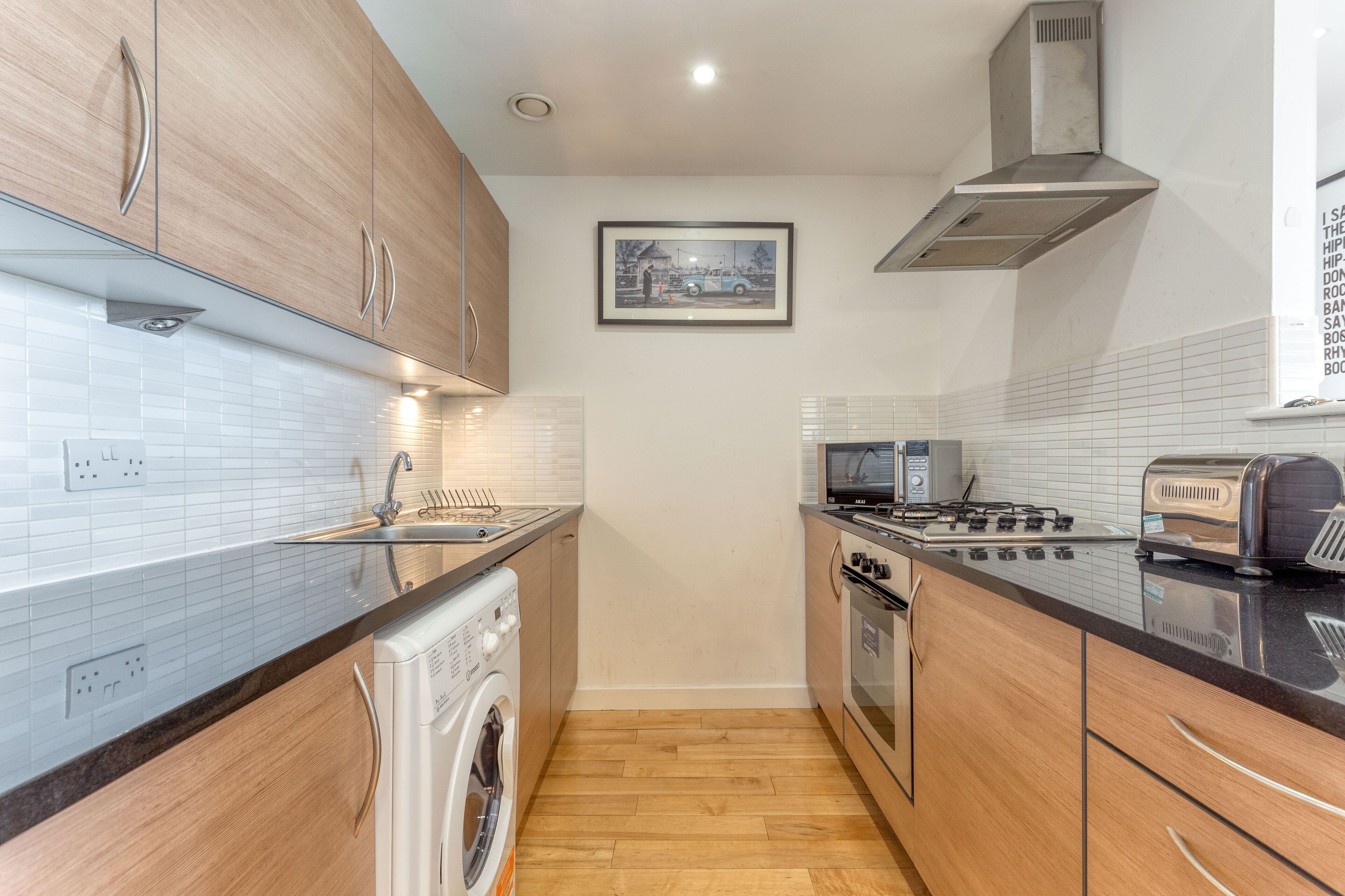A modern kitchen with wooden cabinets, a stainless steel range, a built-in oven, a microwave, and a washing machine.