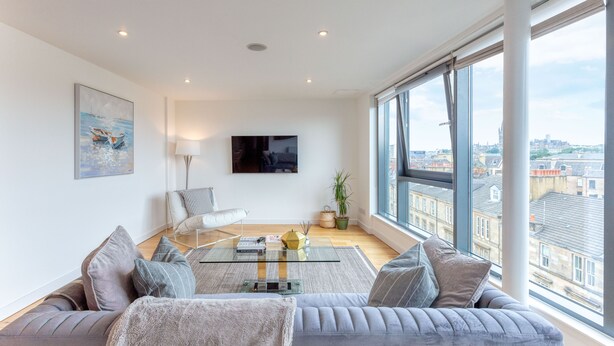 A modern living room with a sofa, a glass coffee table, and a flat-screen TV.