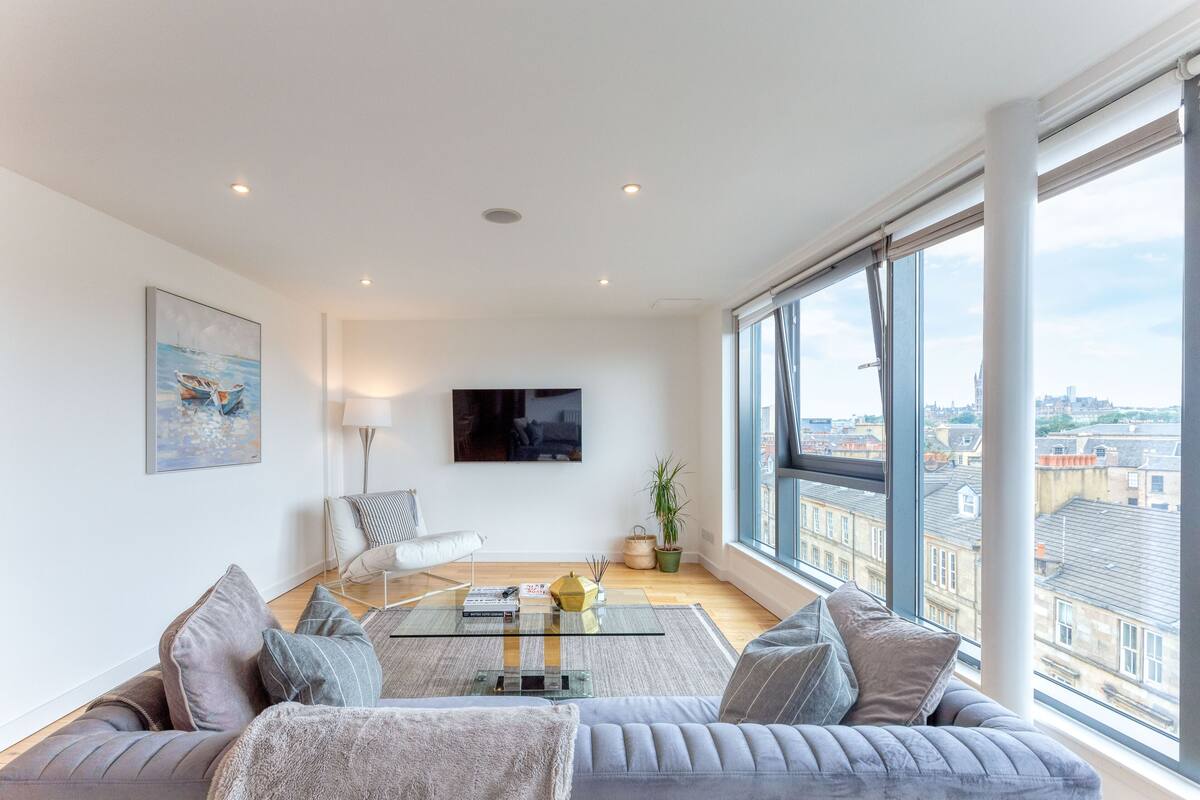 A modern living room with a sofa, a glass coffee table, and a flat-screen TV.