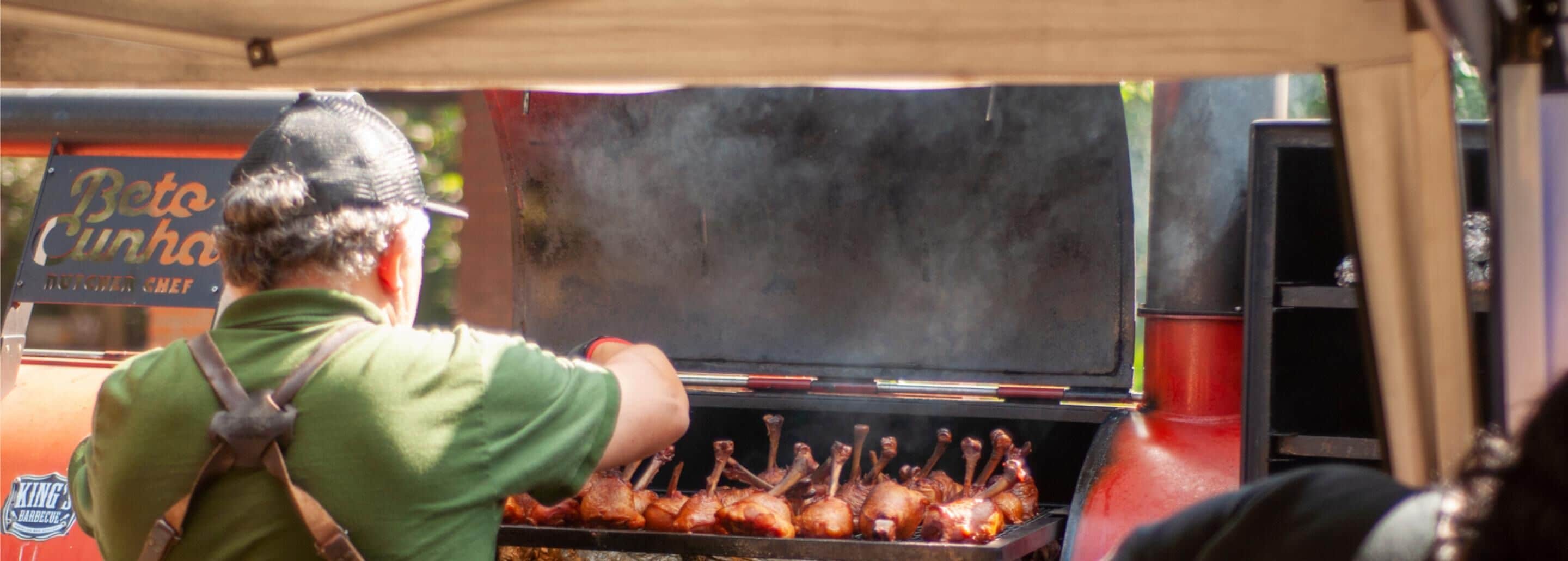 A person grilling meat at a barbecue stand.