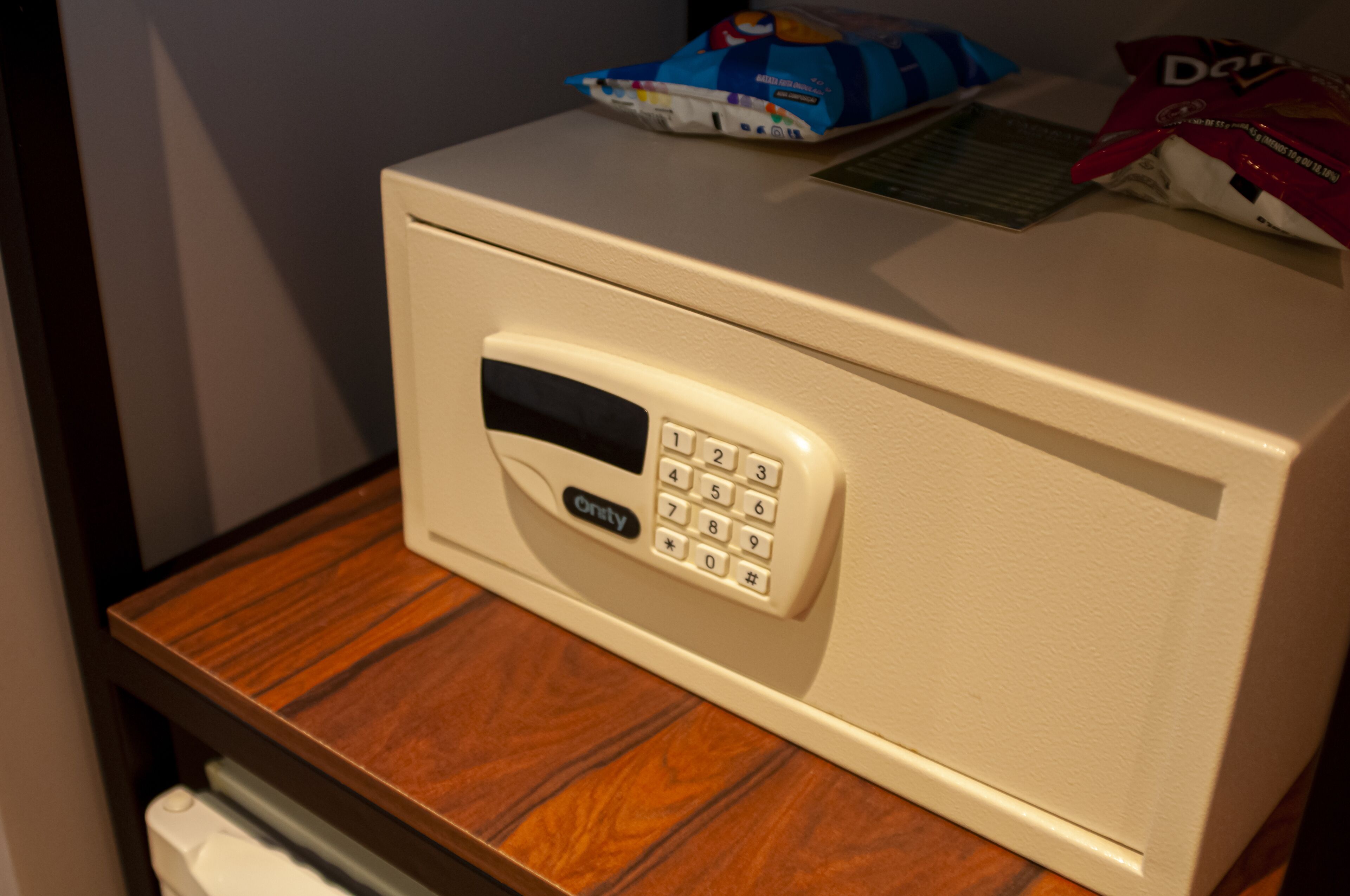 A microwave on a wooden countertop with a digital keypad and a small screen.