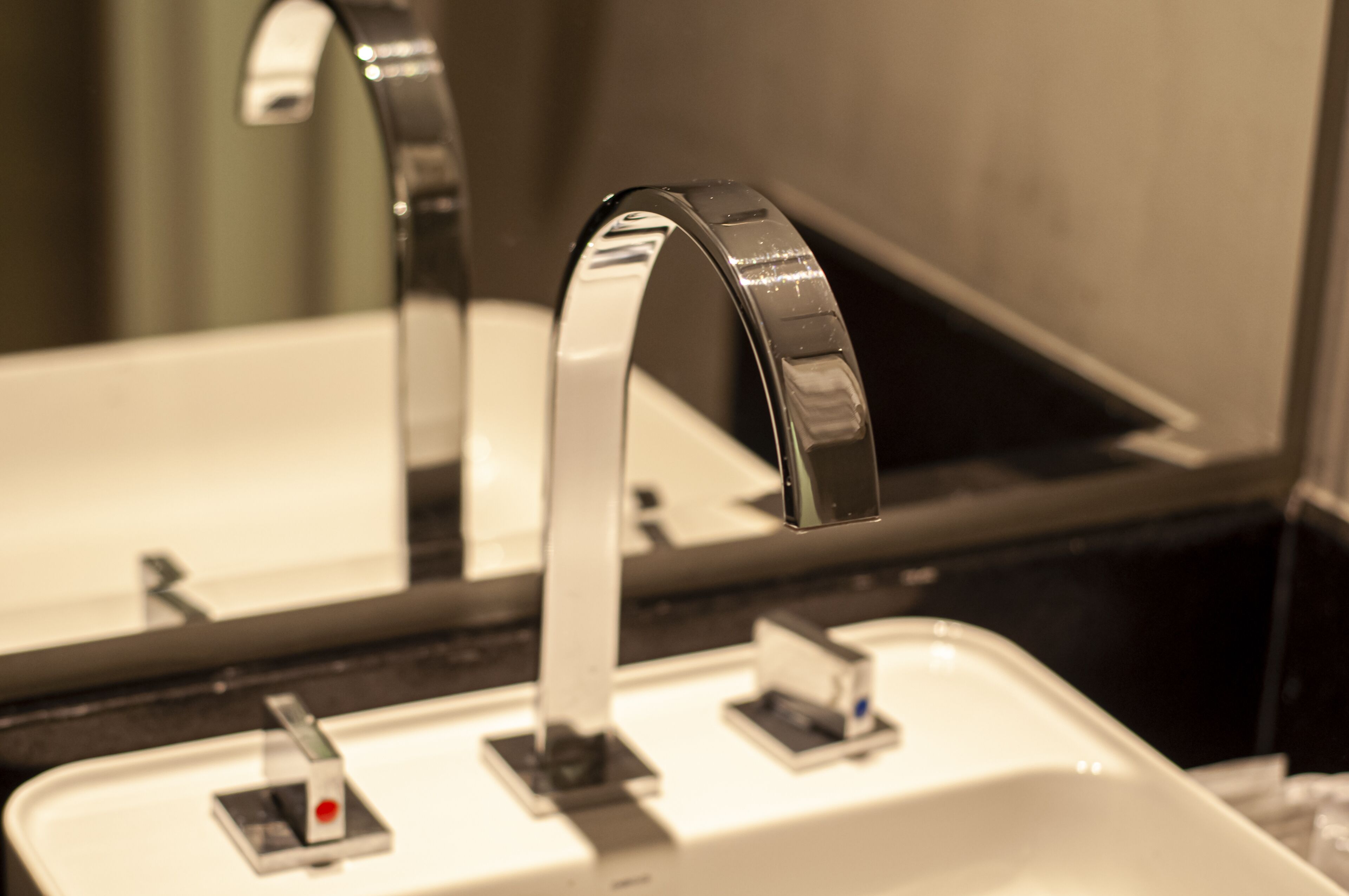 A bathroom sink with a modern faucet and a mirror above it.